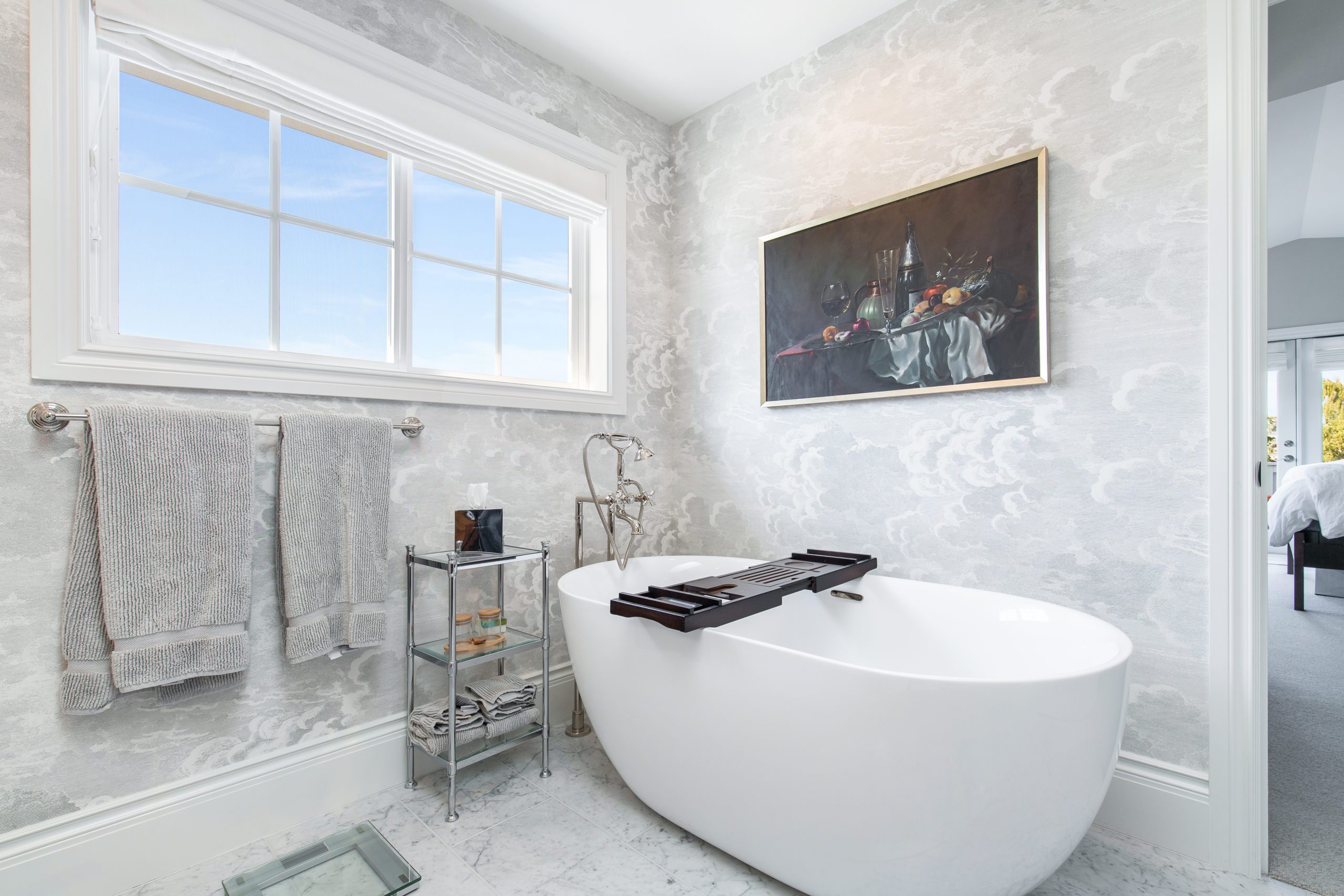 Freestanding white tub with a wall painting and white bathroom wallpaper