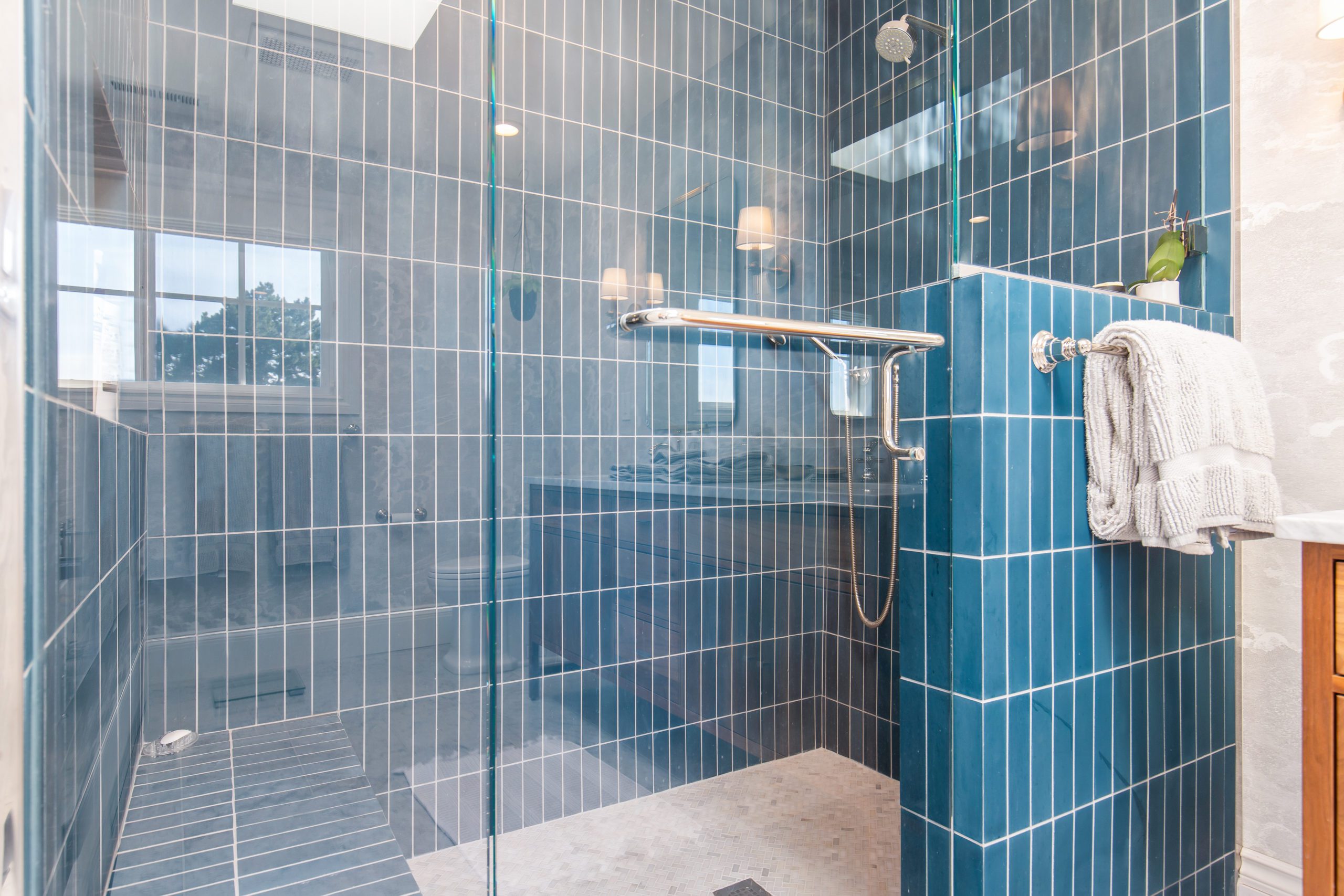 Close up of a shower with glass doors and blue tile