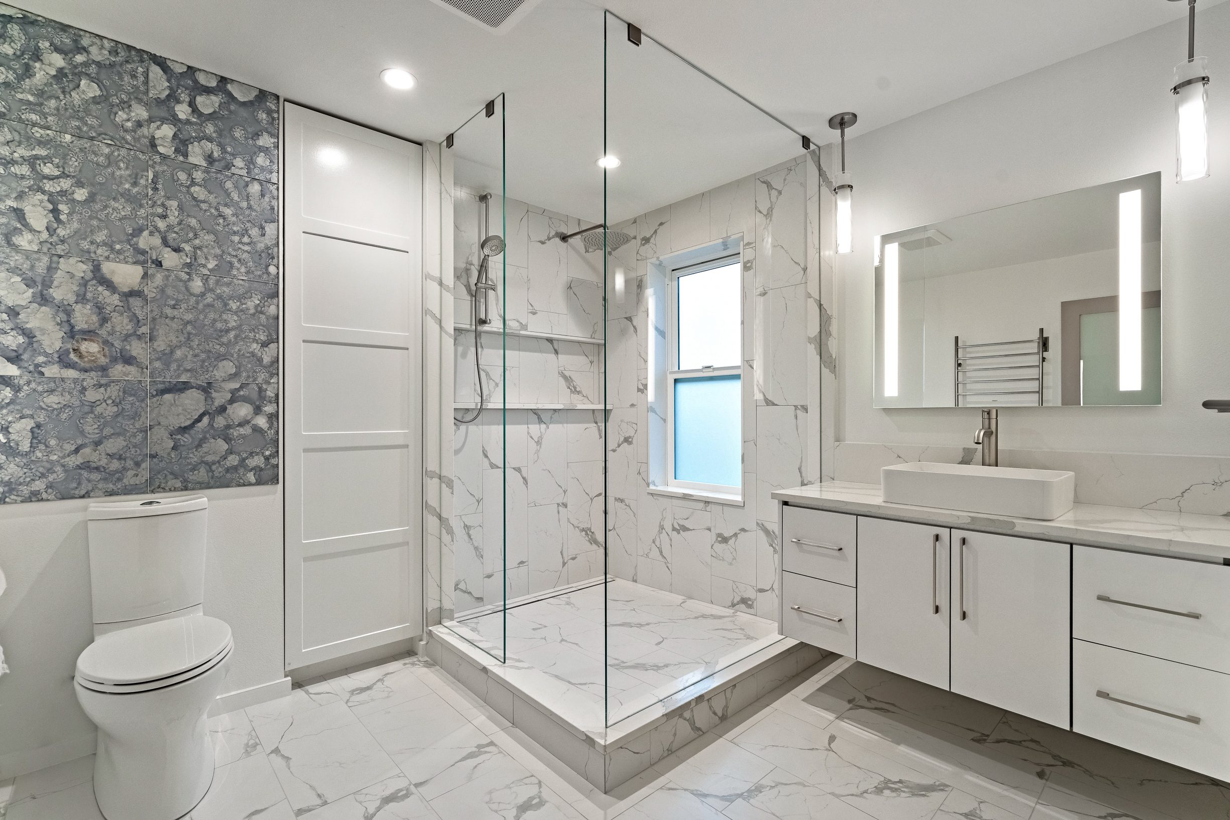 White marble bathroom with rainfall shower and white cabinets