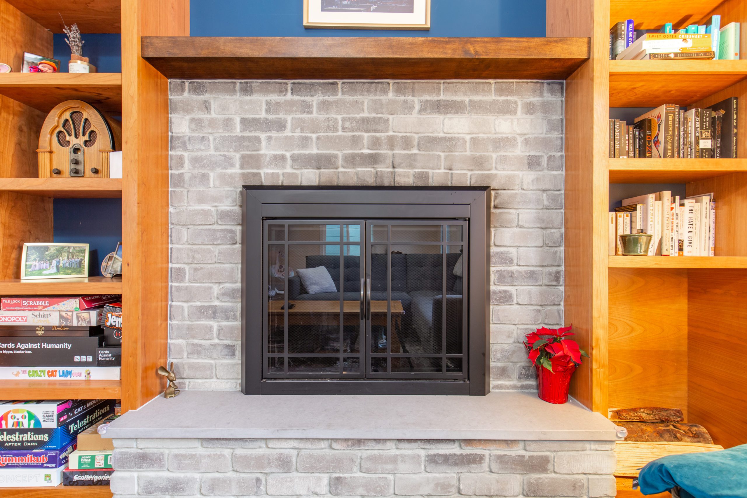 Stone fireplace built into a blue wall with a built in wooden book shelf surrounding the fireplace
