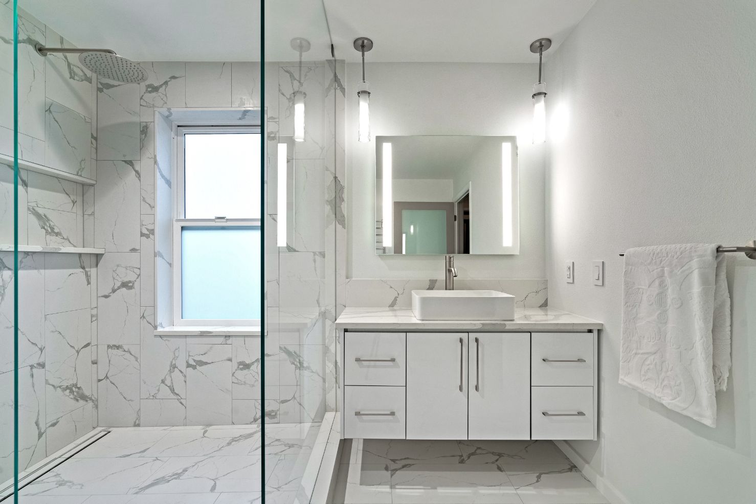 All-white bathroom remodel with large, marble shower and floating custom cabinets as vanity