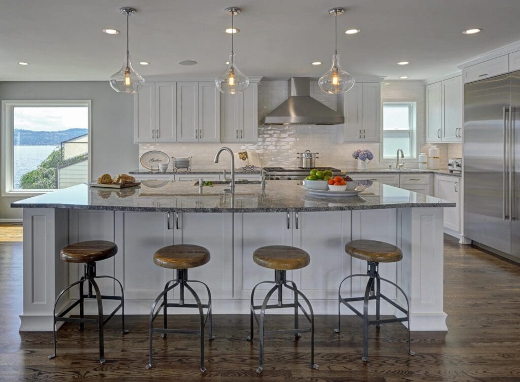 DSC9832a-1-scaled Modern Seattle Waterfront Kitchen Remodel with white cabinets, stainless steel appliances, a large granite island with wooden stools, pendant lights, fruit bowls, and a window showcasing a stunning water view.